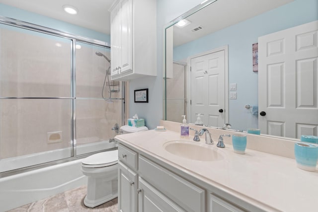 full bathroom with visible vents, toilet, vanity, and shower / bath combination with glass door