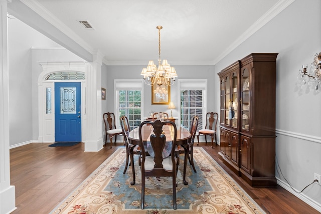 dining space featuring visible vents, dark wood-type flooring, an inviting chandelier, crown molding, and baseboards