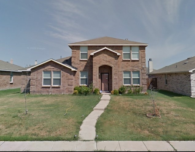 traditional-style house with brick siding and a front lawn