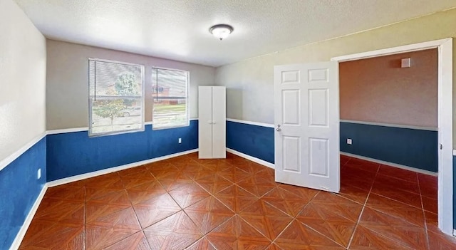 empty room featuring baseboards and a textured ceiling