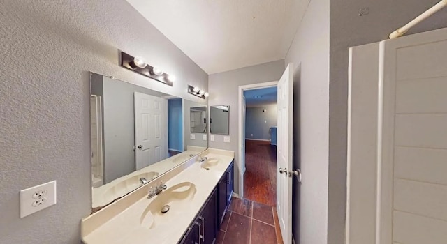 bathroom with vanity, a textured wall, and wood tiled floor