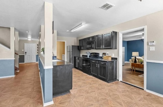 kitchen featuring dark cabinetry, black appliances, baseboards, and visible vents