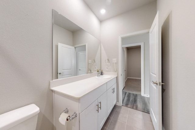 half bath featuring vanity, tile patterned floors, and toilet