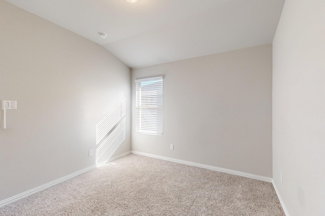 unfurnished room featuring baseboards, light carpet, and vaulted ceiling