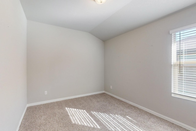 spare room featuring lofted ceiling, carpet flooring, and baseboards