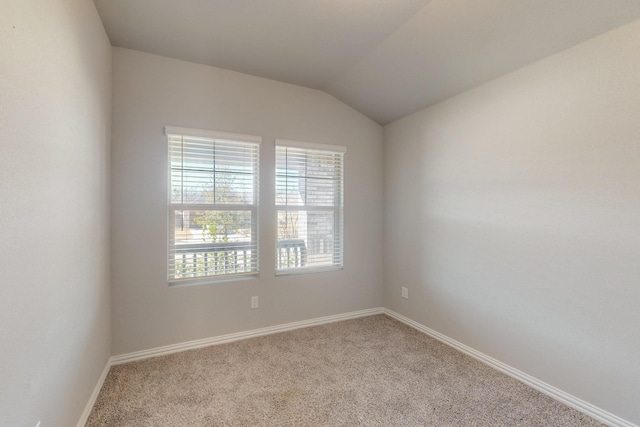 carpeted spare room with baseboards and lofted ceiling