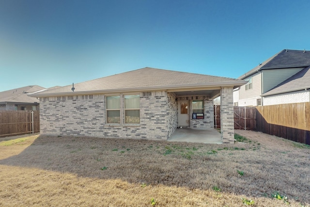 back of house featuring brick siding, roof with shingles, a fenced backyard, and a patio area