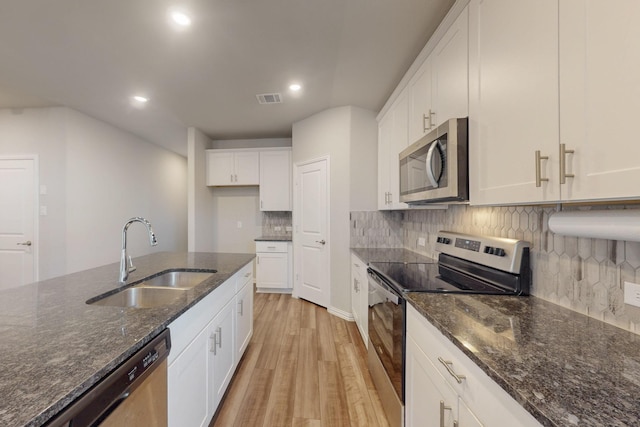 kitchen featuring decorative backsplash, stainless steel appliances, light wood-style floors, white cabinetry, and a sink