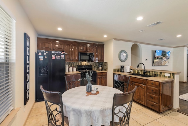 kitchen with visible vents, black appliances, a sink, a peninsula, and light countertops