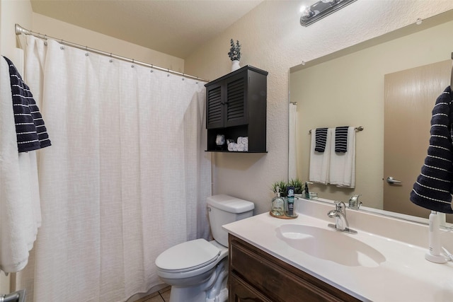 bathroom with vanity, toilet, a textured wall, and tile patterned flooring