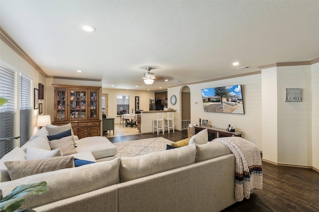 living area featuring ornamental molding, wood finished floors, recessed lighting, arched walkways, and baseboards