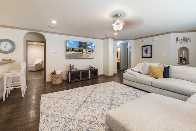 living room with dark wood-type flooring, visible vents, arched walkways, and ornamental molding