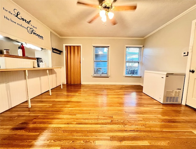 unfurnished living room with baseboards, light wood-style floors, ceiling fan, and crown molding