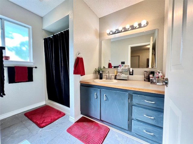 bathroom featuring vanity, a shower with shower curtain, baseboards, and a textured ceiling