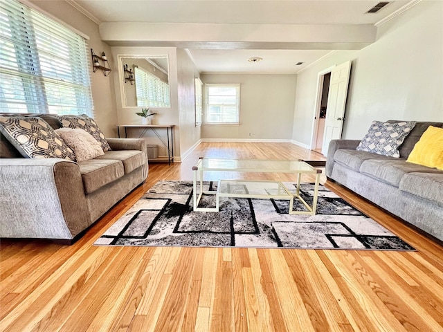 living area featuring visible vents, crown molding, baseboards, and wood finished floors