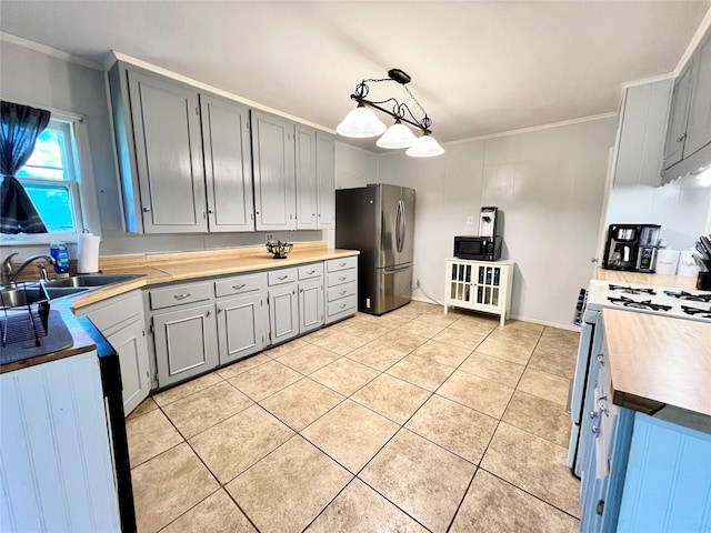 kitchen with light tile patterned floors, range with gas stovetop, gray cabinets, freestanding refrigerator, and a sink