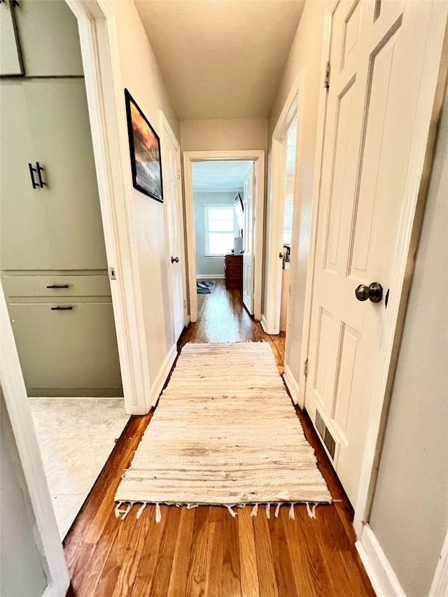 hall with visible vents, baseboards, and dark wood-style flooring