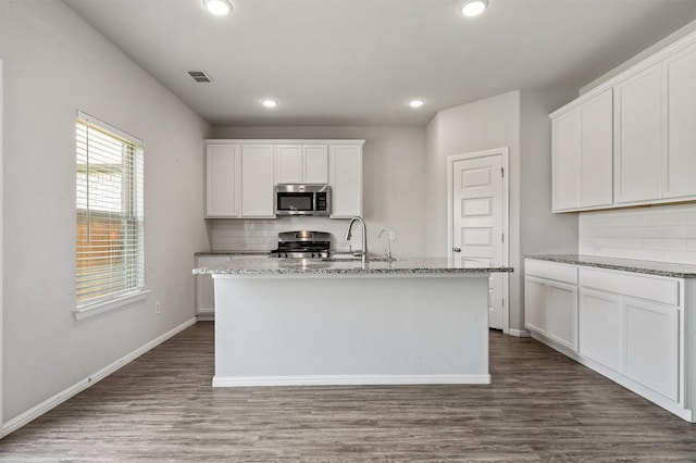 kitchen featuring visible vents, dark wood-type flooring, a sink, light stone counters, and stainless steel appliances