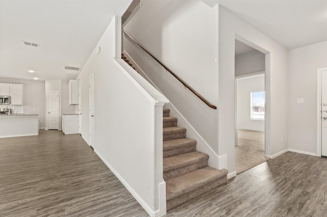 staircase with visible vents, baseboards, and wood finished floors