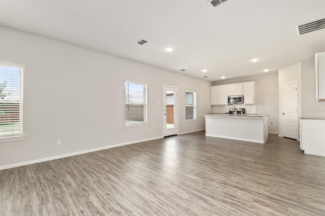 unfurnished living room featuring wood finished floors, visible vents, and a wealth of natural light