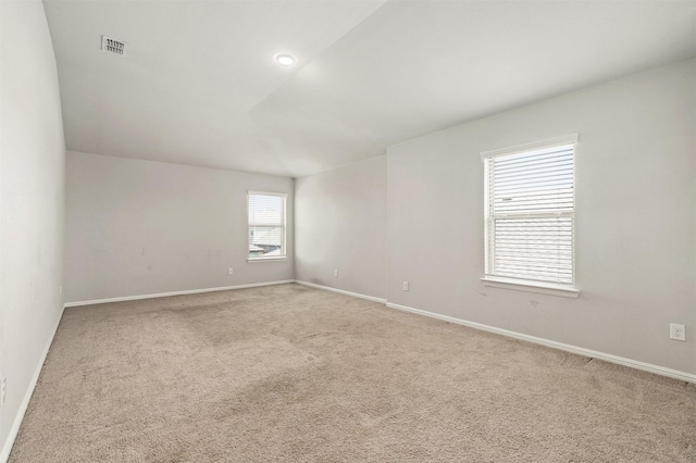 carpeted spare room with visible vents and baseboards