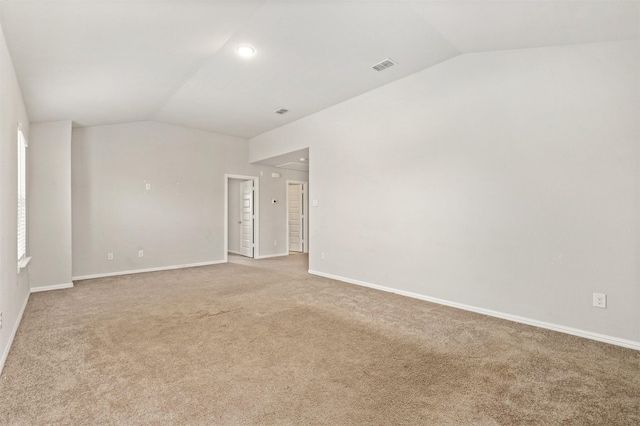 spare room featuring baseboards, visible vents, lofted ceiling, and light carpet