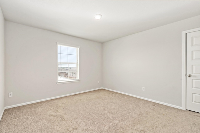 unfurnished room featuring light colored carpet and baseboards