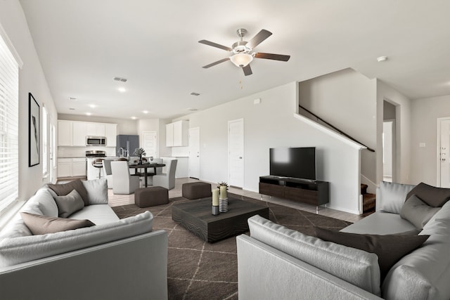 living area featuring visible vents, baseboards, recessed lighting, ceiling fan, and stairs