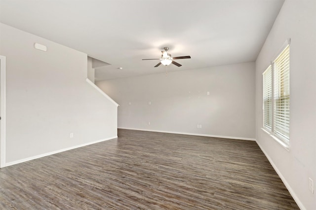 empty room featuring baseboards, dark wood-style flooring, and ceiling fan