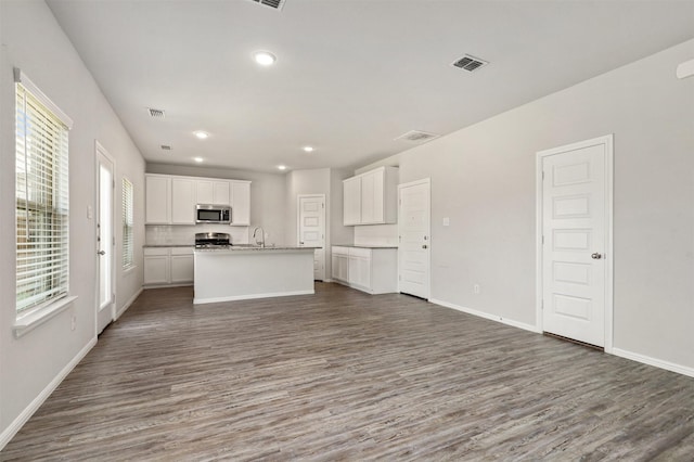 kitchen featuring visible vents, a sink, wood finished floors, stainless steel appliances, and white cabinets