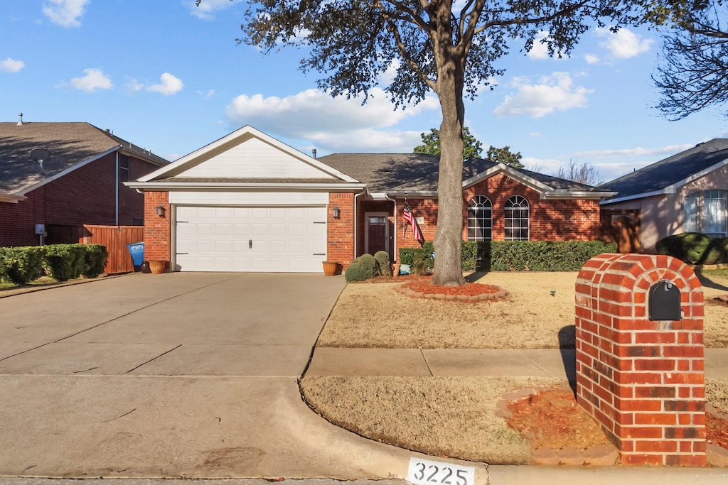 ranch-style home featuring brick siding, an attached garage, and concrete driveway