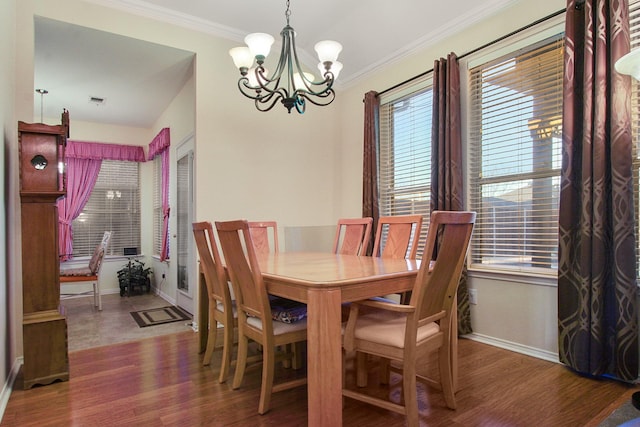 dining area featuring wood finished floors, visible vents, baseboards, an inviting chandelier, and ornamental molding