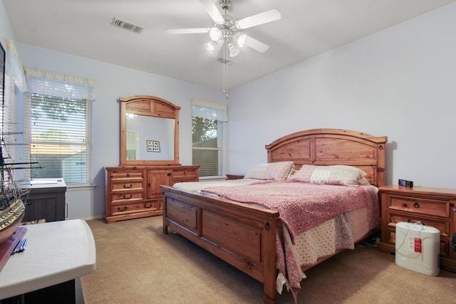 bedroom with visible vents, light colored carpet, ceiling fan, and multiple windows