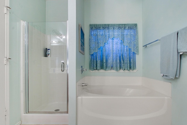 bathroom featuring a stall shower and a bath