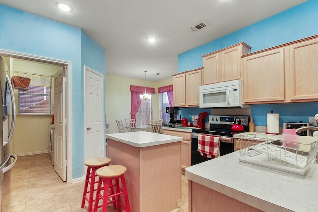 kitchen with visible vents, light brown cabinetry, a kitchen island, appliances with stainless steel finishes, and light countertops