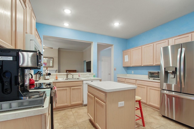 kitchen featuring light countertops, light brown cabinets, appliances with stainless steel finishes, and a sink