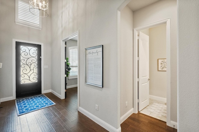 foyer featuring dark wood finished floors, baseboards, and a chandelier