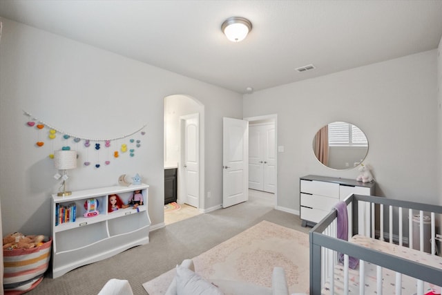 bedroom featuring baseboards, visible vents, arched walkways, a nursery area, and light colored carpet