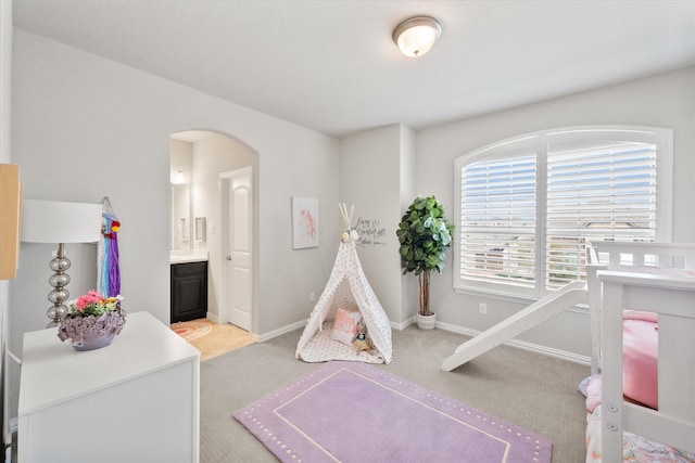 game room featuring baseboards, arched walkways, and carpet floors