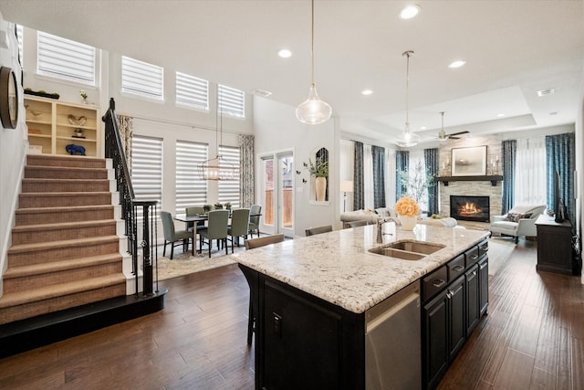 kitchen featuring dark wood-style flooring, dishwasher, a fireplace, and a sink