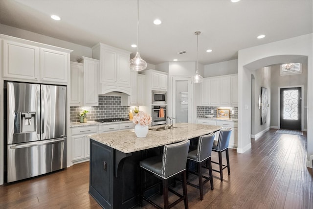 kitchen featuring white cabinets, arched walkways, and stainless steel appliances