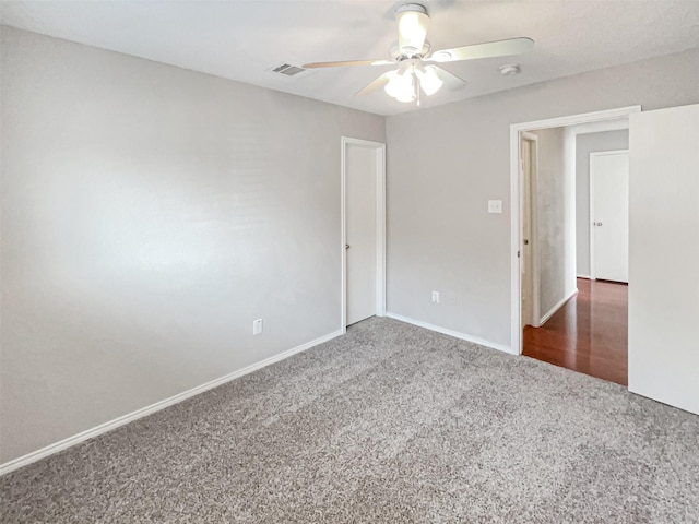 carpeted spare room with a ceiling fan, visible vents, and baseboards