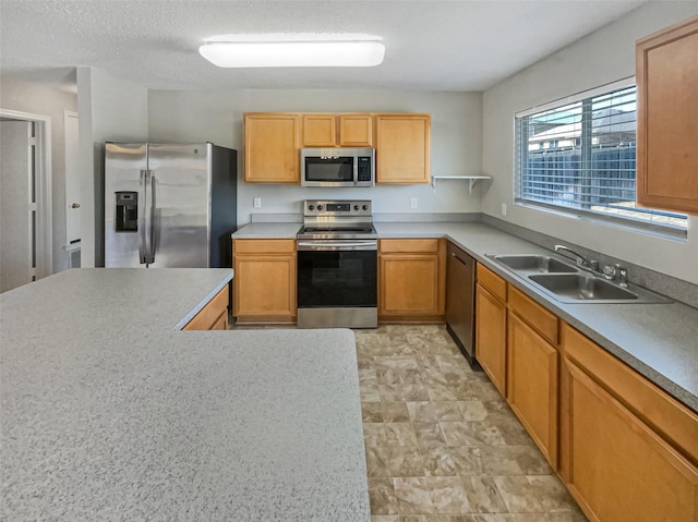 kitchen with a textured ceiling, light countertops, appliances with stainless steel finishes, and a sink