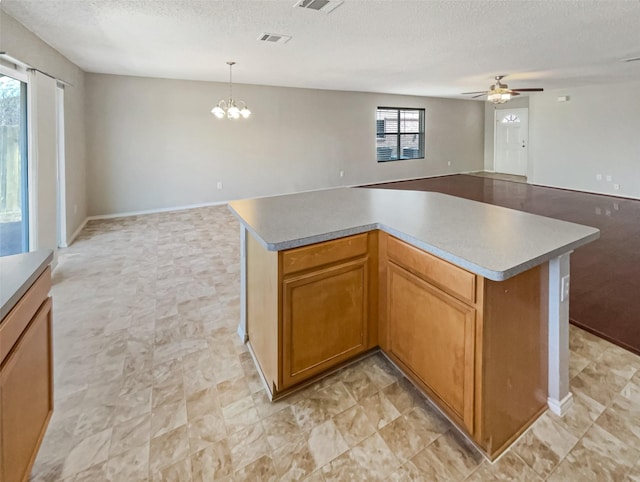 kitchen featuring a kitchen island, a textured ceiling, open floor plan, and ceiling fan with notable chandelier