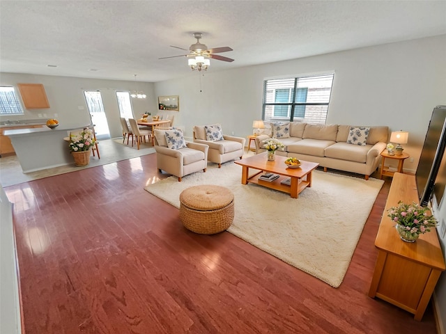 living area with a wealth of natural light, a textured ceiling, a ceiling fan, and light wood finished floors