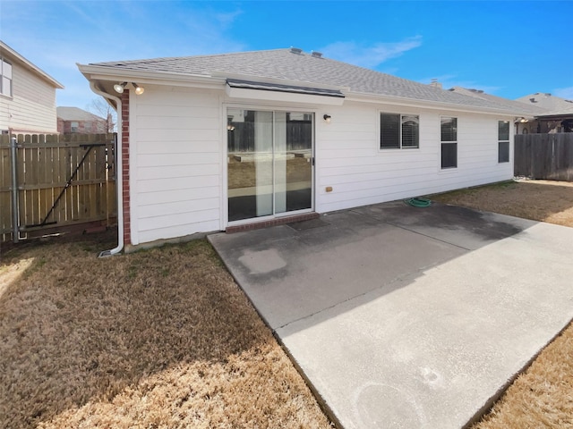 back of property with a yard, a patio, roof with shingles, and fence