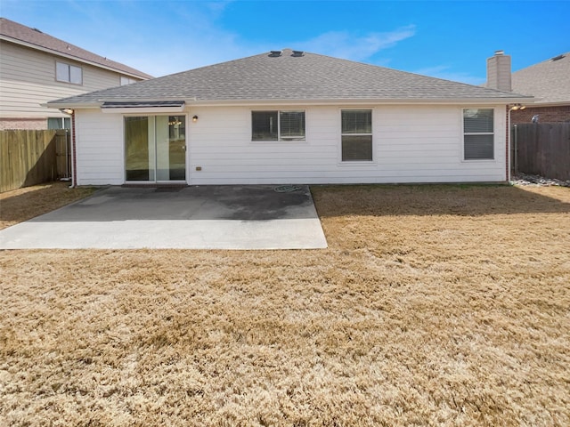 rear view of property featuring a yard, a shingled roof, a fenced backyard, and a patio area