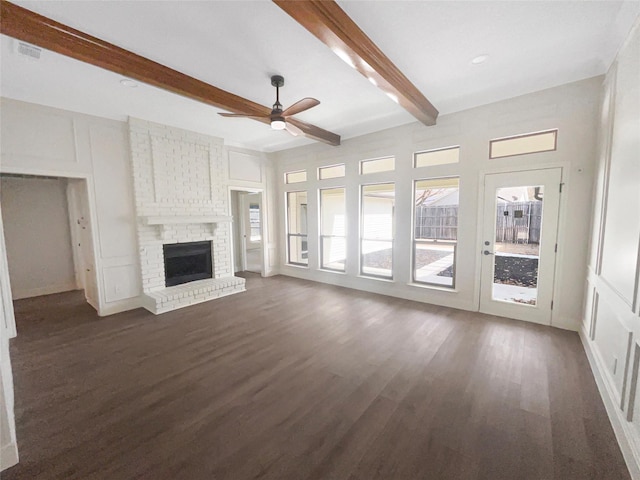 unfurnished living room with visible vents, a brick fireplace, ceiling fan, beam ceiling, and dark wood-style floors