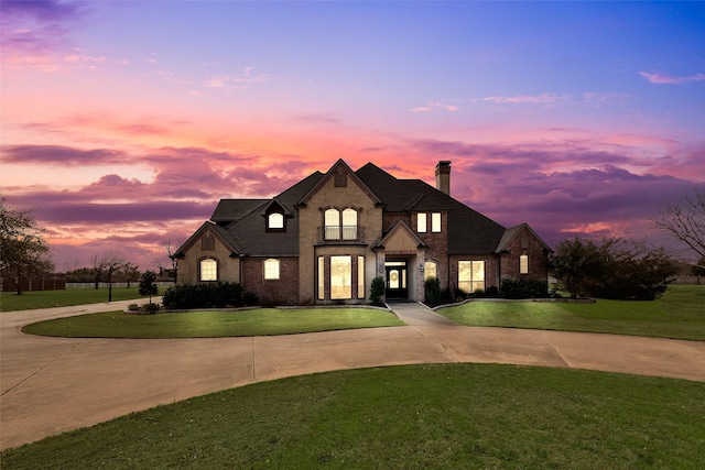 french provincial home with a front yard, brick siding, and curved driveway