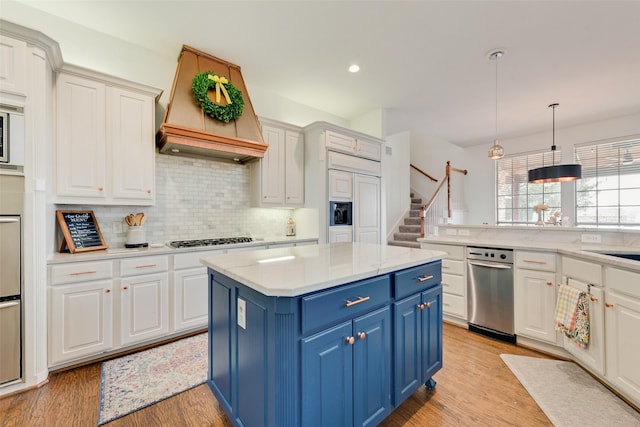 kitchen featuring a center island, custom range hood, light wood-style flooring, gas stovetop, and blue cabinets